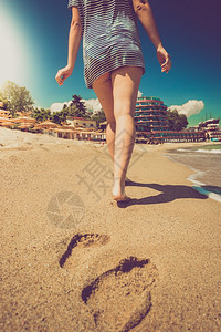 在阳光明媚的下在沙滩上行走的孤独女人图片
