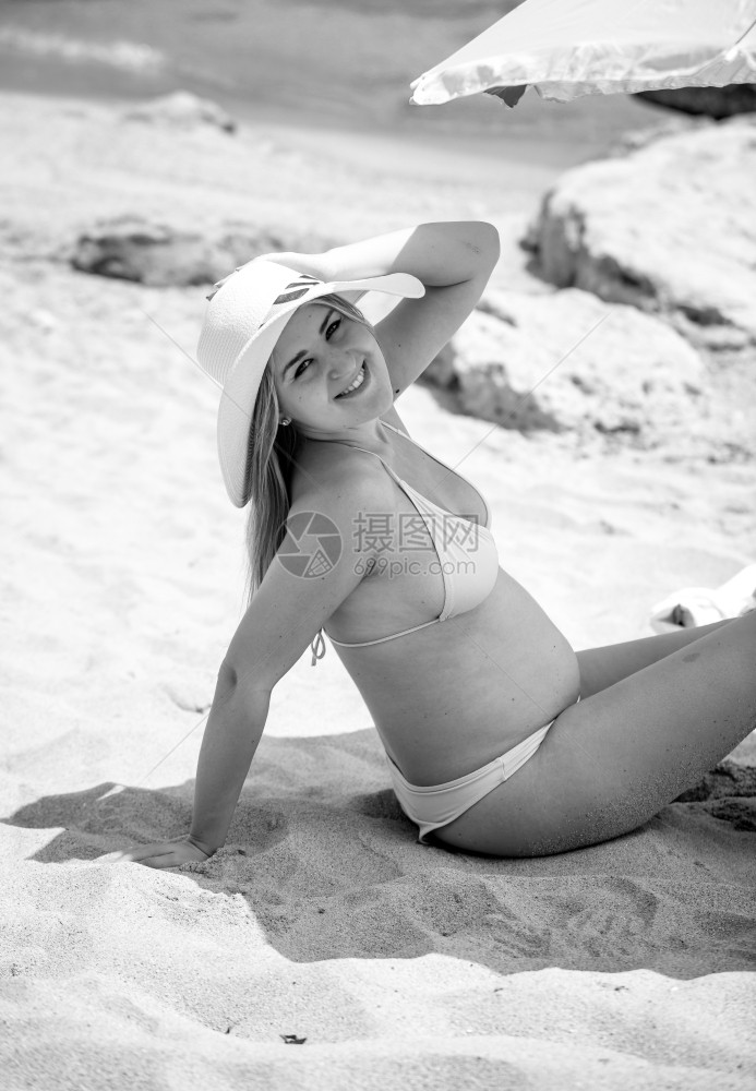 美丽的孕妇在沙滩上冒阳伞的黑白肖像图片
