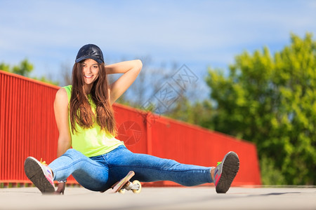 酷的十几岁女孩滑板坐在街上户外图片