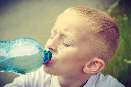 小男孩儿小口渴的男孩儿在户外用塑料瓶喝水背景
