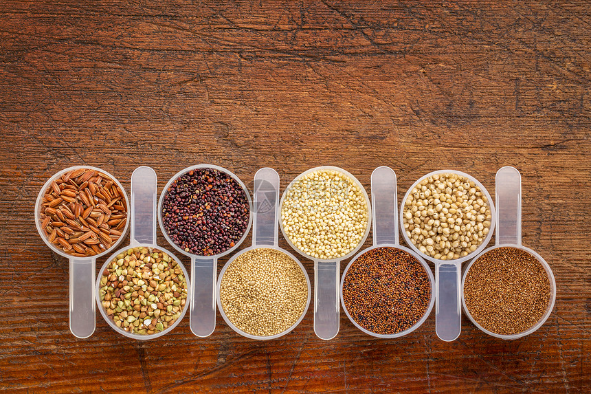 免费谷类quinoa棕稻Kaniwaamaranth高梁小米麦一连串测量生锈木上勺子和复制空间图片