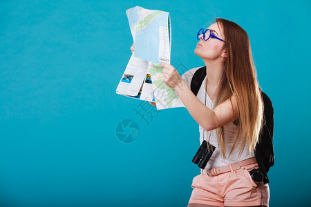 暑假和旅游概念有趣的年轻女子长发太阳眼镜背包蓝色阅读图片
