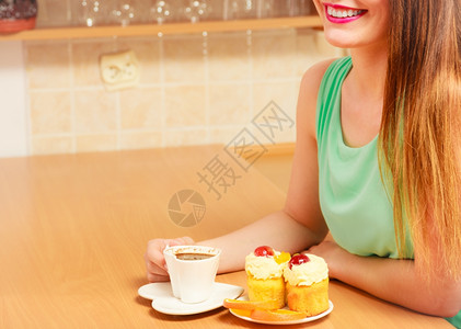 有咖啡和美味食的甜奶油蛋糕和橙色格鲁顿女孩坐在厨房喝热饮料吃早餐图片
