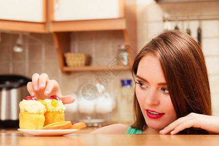 渴求女人吃甜的蛋糕奶油和水果上面的和手指美味贪食的概念甜背景