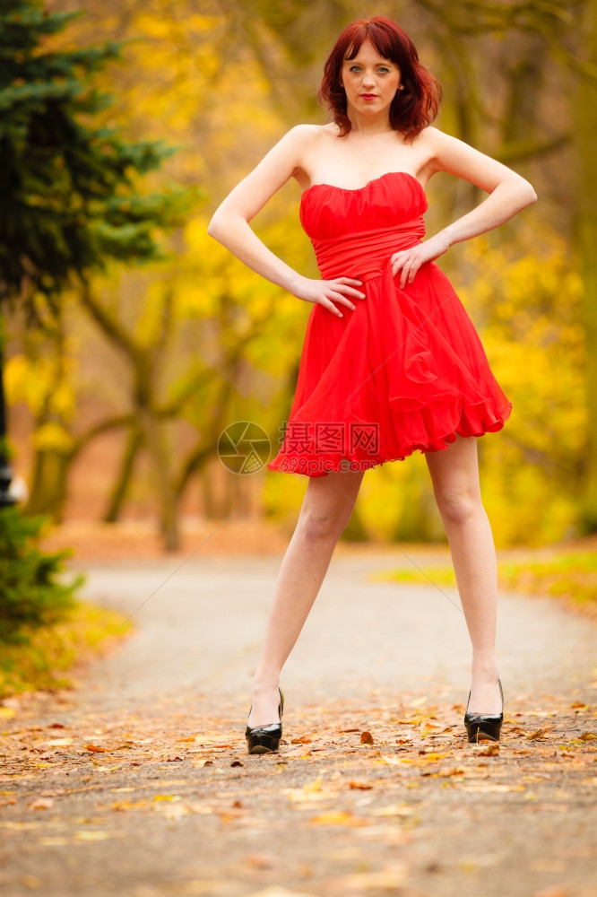 穿着红裙子的全长时装优雅的年轻女子户外放松在秋季公园散步图片