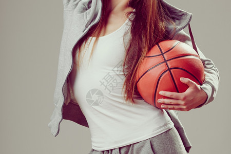 穿着戴头罩的运动服装穿着篮球运动的少女图片