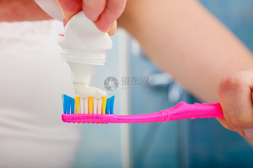口腔保健近身女手拿着牙刷在上面涂膏图片
