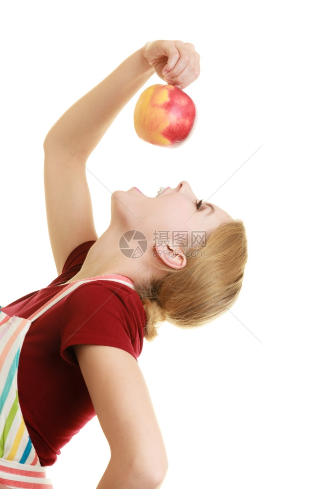 穿着条纹厨房围裙的有趣家庭主妇或厨师吃着孤立的红苹果健康水图片