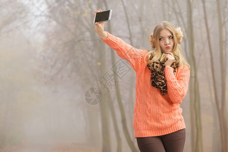 可爱的时装女郎在公园拍自照片可爱的时装女郎在秋天公园拍自照片图片