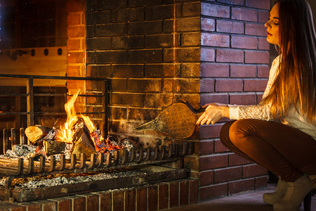 波纹管在家里的壁炉放火女人们用钟头放火的女人们年轻孩暖和放松家里冬天背景