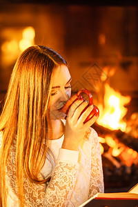 女人在壁炉喝咖啡读书女孩喝热饮料放松暖气图片