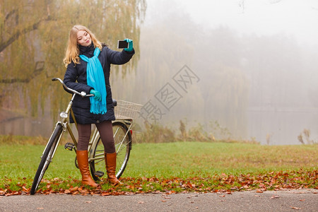 快乐的女子在公园里骑自行车拍快乐的年轻女子在秋天公园拍自行车图片