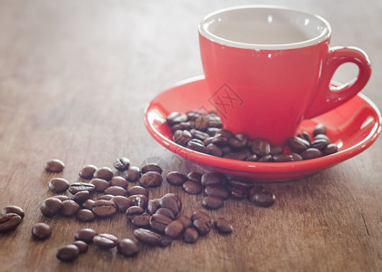 红咖啡杯和木制桌上的咖啡豆股票照片图片