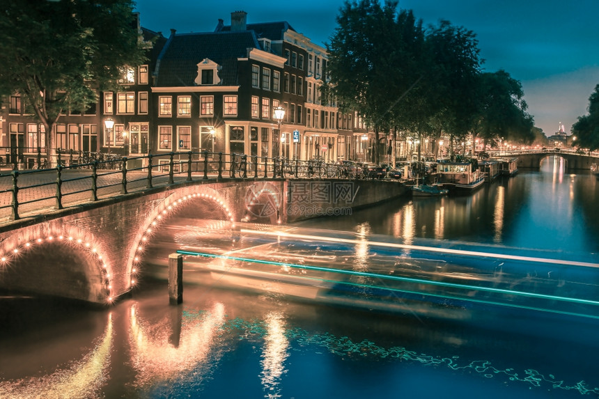 荷兰阿姆斯特丹运河桥梁和典型房屋船只和自行车的夜间城市景色图片