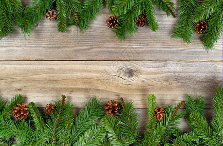 圣诞边框架的顶部和底有松树枝和圆锥在生木板上以水平格式布局图片