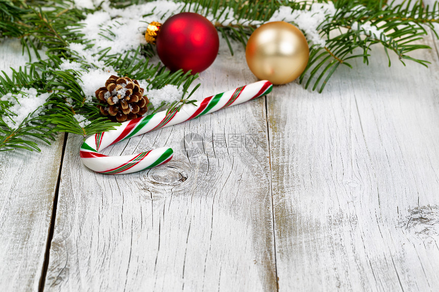 用雪覆盖的糖果甘蔗真正的法尔树枝装饰品锥形和雪在生锈的白木板上圣诞季节概念关注糖果甘蔗的前面部分图片