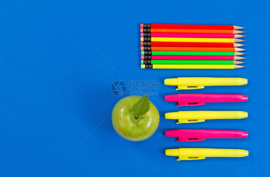 办公室或返回学校用品包括绿色苹果亮点标志和蓝底彩色铅笔图片
