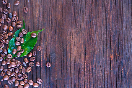 木制桌上的咖啡豆和叶子图片