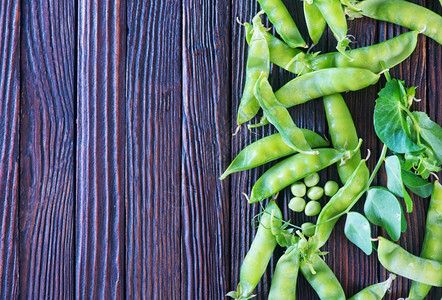 桌子上的绿豆木制背景上的新鲜豆子图片