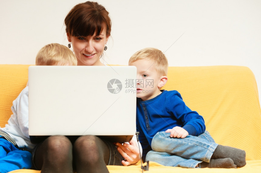快乐的家庭使用笔记本电脑坐在沙发上图片