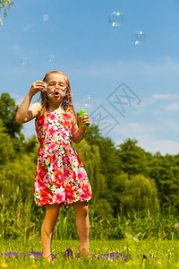 小女孩吹肥皂泡在户外小孩公园玩得开心快乐和无忧虑的童年图片