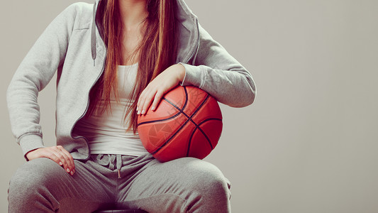 穿着戴头罩的运动服装穿着篮球运动的少女图片