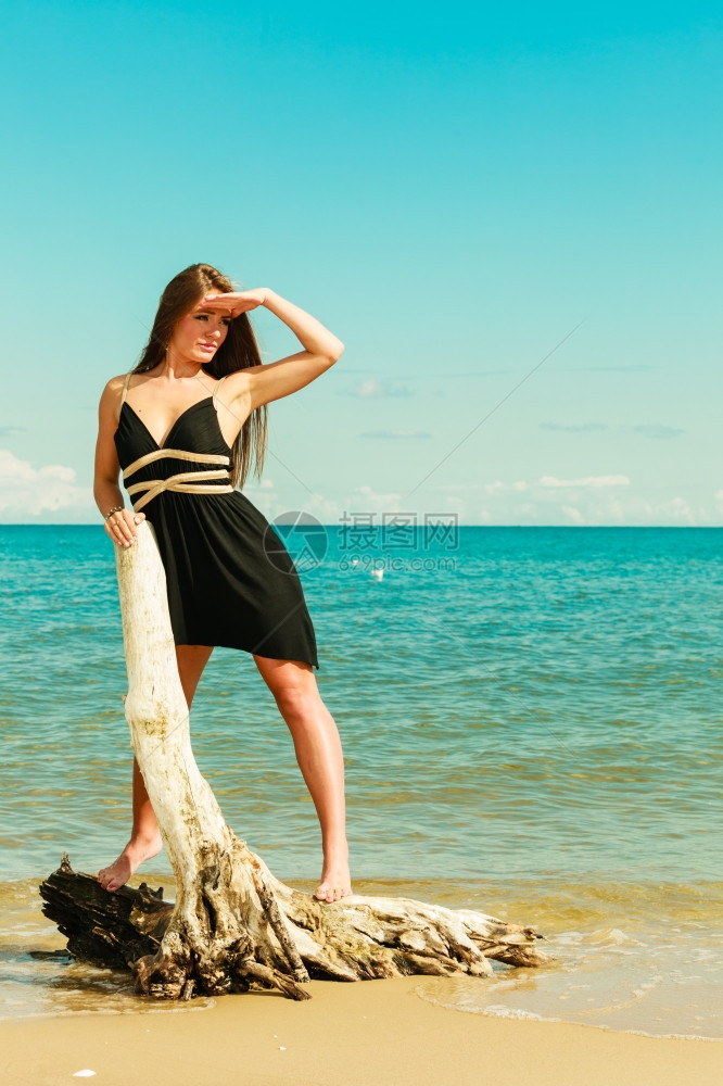 假期旅行和自由概念海滩上长头发的漂亮感美女长发穿暑期服装的年轻漂亮棕色女子在海边放松站干树根上图片