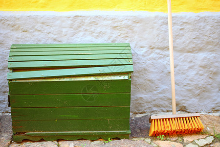 门外大绿色木箱和红扫把用于在混凝土墙背景上做家务背景图片
