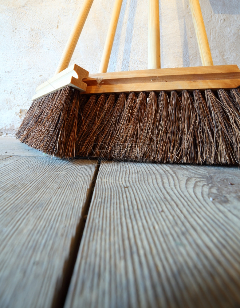 关闭大型扫帚在乡间房屋的老木制地板上做家务图片
