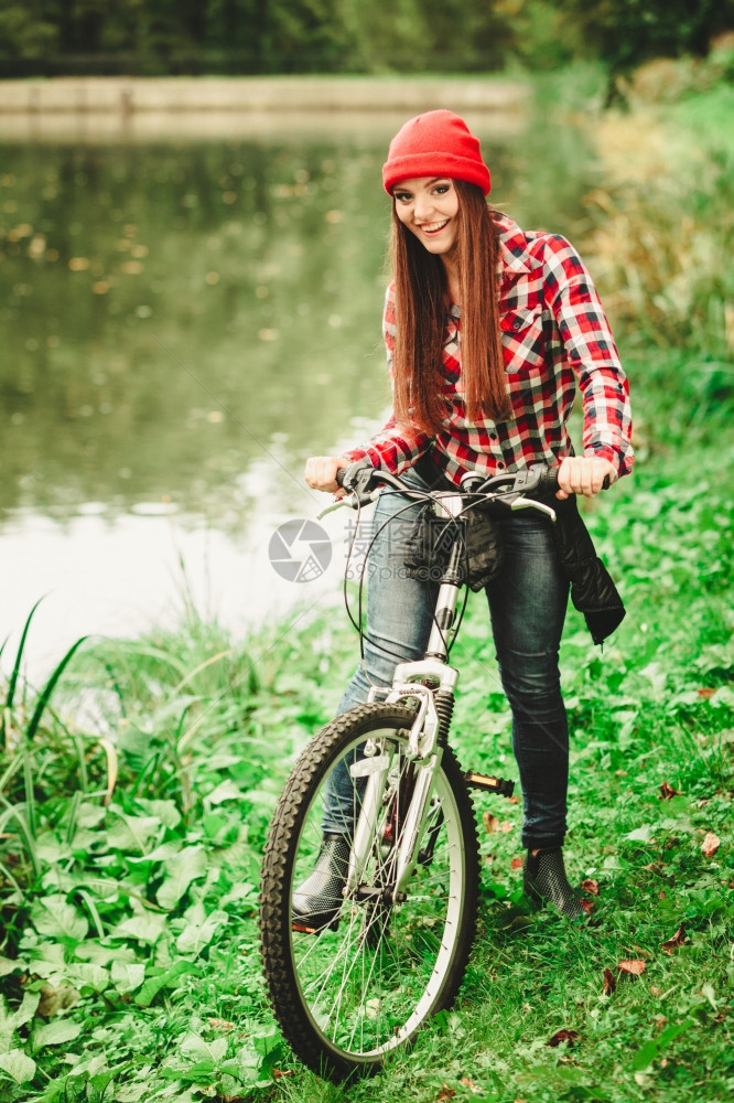 戴帽子的女人骑自行车在水潭边休息图片