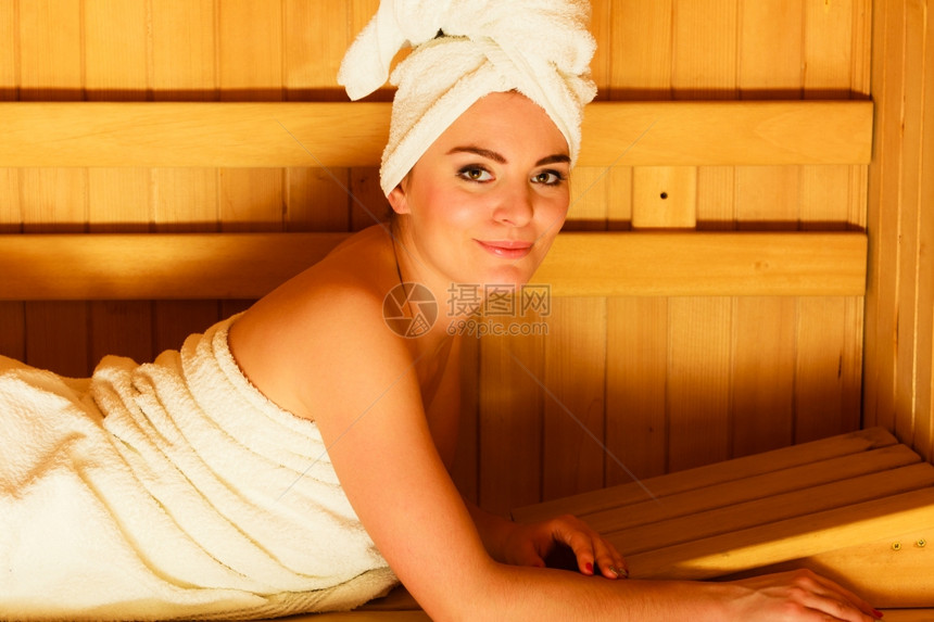 穿着全长白毛巾的女子躺在木制芬尼桑拿放松地躺在木制芬尼桑拿图片