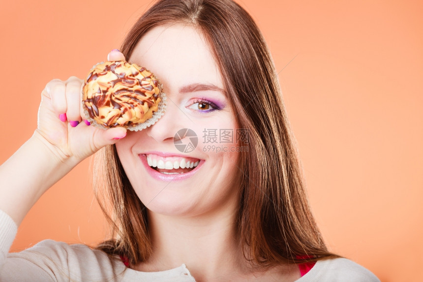 有趣的女人拿着蛋糕玩得开心用蛋糕橙色背景遮住她的眼睛图片