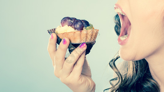 甜美的食物浸泡和脂肪的概念妇女面对张开的嘴吃蛋糕用过滤的照片背景图片