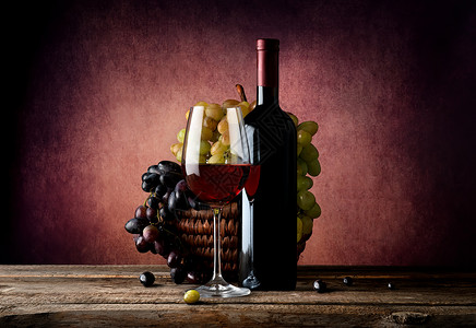 红酒和一篮子葡萄放在桌上图片