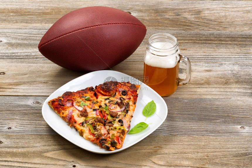 两片新鲜烤披萨在白色盘子里橄榄球和一品脱纯净倒的啤酒放在生锈的木制桌子上xA图片