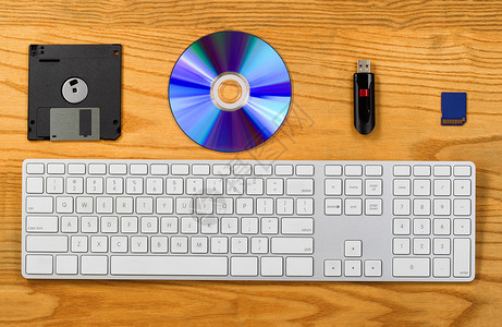 用键盘软CD拇指驱动器和闪存盘对桌面的顶端视图带有技术变化的便携式数据存储装置的概念背景