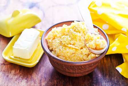 玉米粥和木制桌上的黄油背景图片