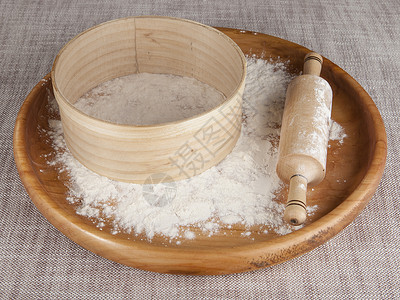 在木盘上的面粉打滚针和筛子在美丽的桌布上作成关于烹饪美食的杂志照片图片