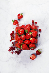 红色透明透明塑料托盘配有新鲜采摘的草莓背景