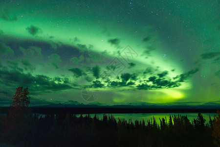 地磁北极光从遥远的阿拉斯加云中浮现出来背景