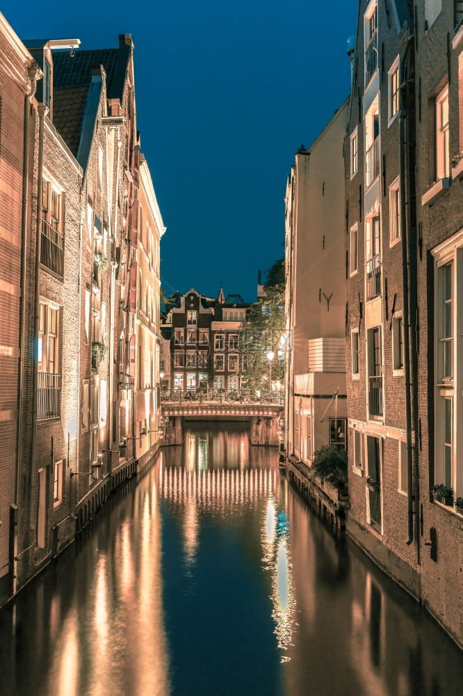 荷兰阿姆斯特丹运河桥典型房屋和自行车的夜间城市景色图片