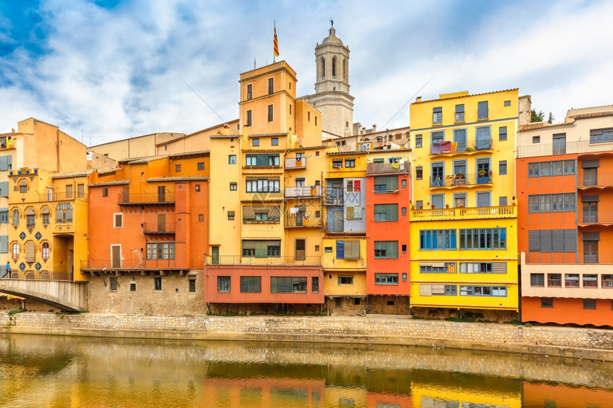 印有加泰罗尼亚的多彩黄色红和橙房屋反映在西班牙加泰罗尼亚州吉纳的奥尼亚尔河水中位于西班牙加泰罗尼亚的圣玛丽大教堂背景之下图片