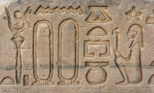 文字光雕刻在石头上的古老象形文字埃及寺庙墙的详情背景