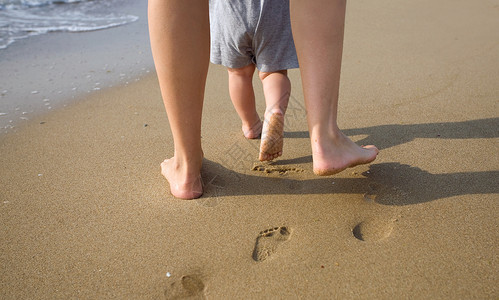 母亲帮助让孩子在海滩上迈出第一步图片