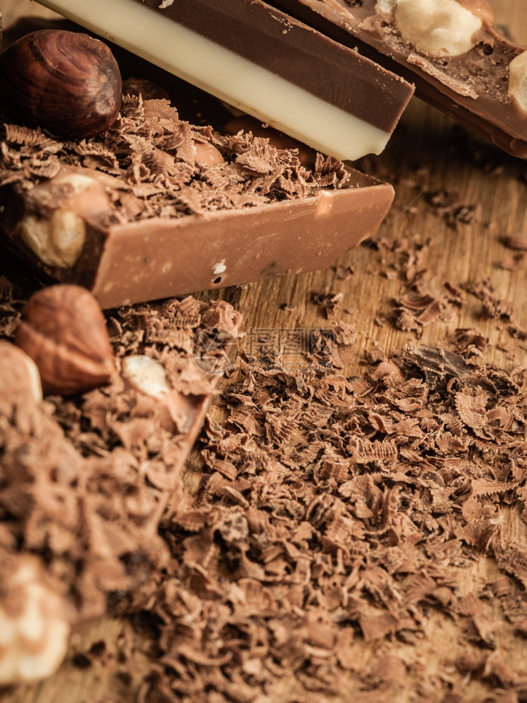 不同的巧克力和剃须卷发木制桌上有很多巧克力图片
