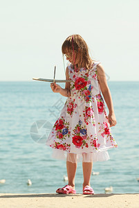 小女孩在海边玩纸板飞机图片