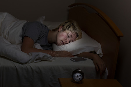 少女睡在夜间摊位上带着手机睡觉青少年被技术包围甚至深夜图片