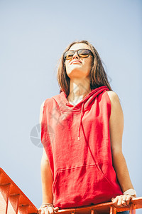 长发的年轻女孩带着太阳眼镜在城市桥上骑栏长大夏天时图片