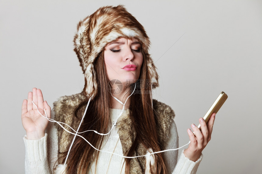 冬季女孩享受音乐冬季女孩用耳机电话听音乐图片