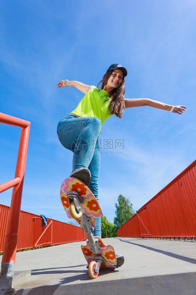 玩暑期运动和积极生活方式穿着全身滑板的酷少女在街上玩滑板外面图片